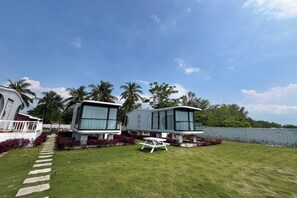 A modern vacation home with a paved pathway leading to a white picnic table. - Saga Village Hotel & Resort Bintan By Zuzu (Bintan)