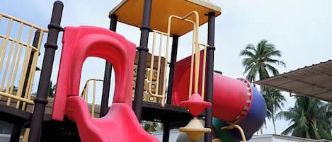 A playground with a red slide, a yellow climbing structure, and a red and blue ball pit.