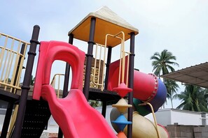 A playground with a red slide, a yellow climbing structure, and a red and blue ball pit. - Saga Village Hotel & Resort Bintan By Zuzu (Bintan)