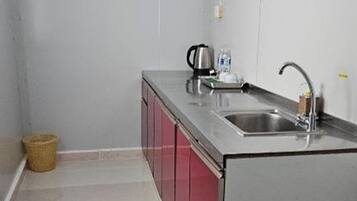 A small kitchen with a sink, a kettle, and a basket.