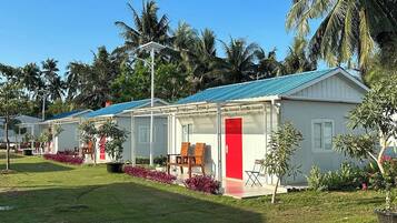 A row of white buildings with blue roofs, surrounded by lush greenery and palm trees.