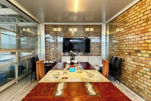 A conference room with a long wooden table, glass partitions, a brick wall, and a mounted television. - Saga Village Hotel & Resort Bintan By Zuzu (Bintan)