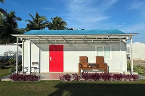 A small building with a red door, two wooden chairs, and a covered porch. - Saga Village Hotel & Resort Bintan By Zuzu (Bintan)