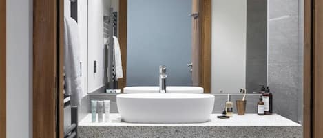 A modern bathroom with a large white sink, wooden beams, and a mirror.