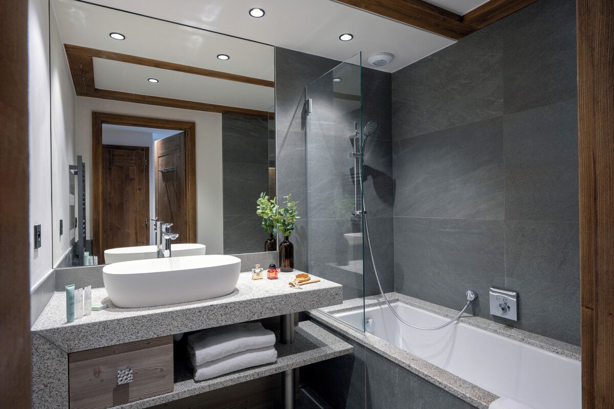 A modern bathroom with a large white sink, a glass shower enclosure, and a bathtub.