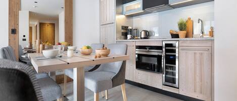 A modern kitchen with wooden cabinets, a built-in oven, and a dining area with a wooden table and chairs.