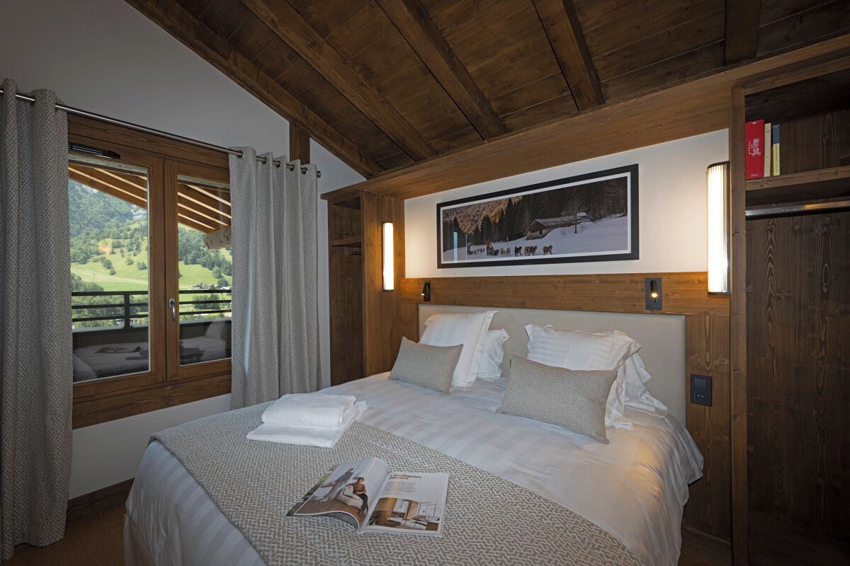 A bedroom with a large bed, a framed picture on the wall, and a window with curtains.