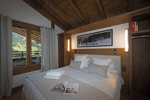A bedroom with a large bed, a framed picture on the wall, and a window with curtains. - MGM Hôtels et Résidences - Hotel Laska (Les Contamines-Montjoie)