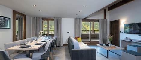 Un salon moderne comprenant un coin repas, de grandes fenêtres et un téléviseur à écran plat.