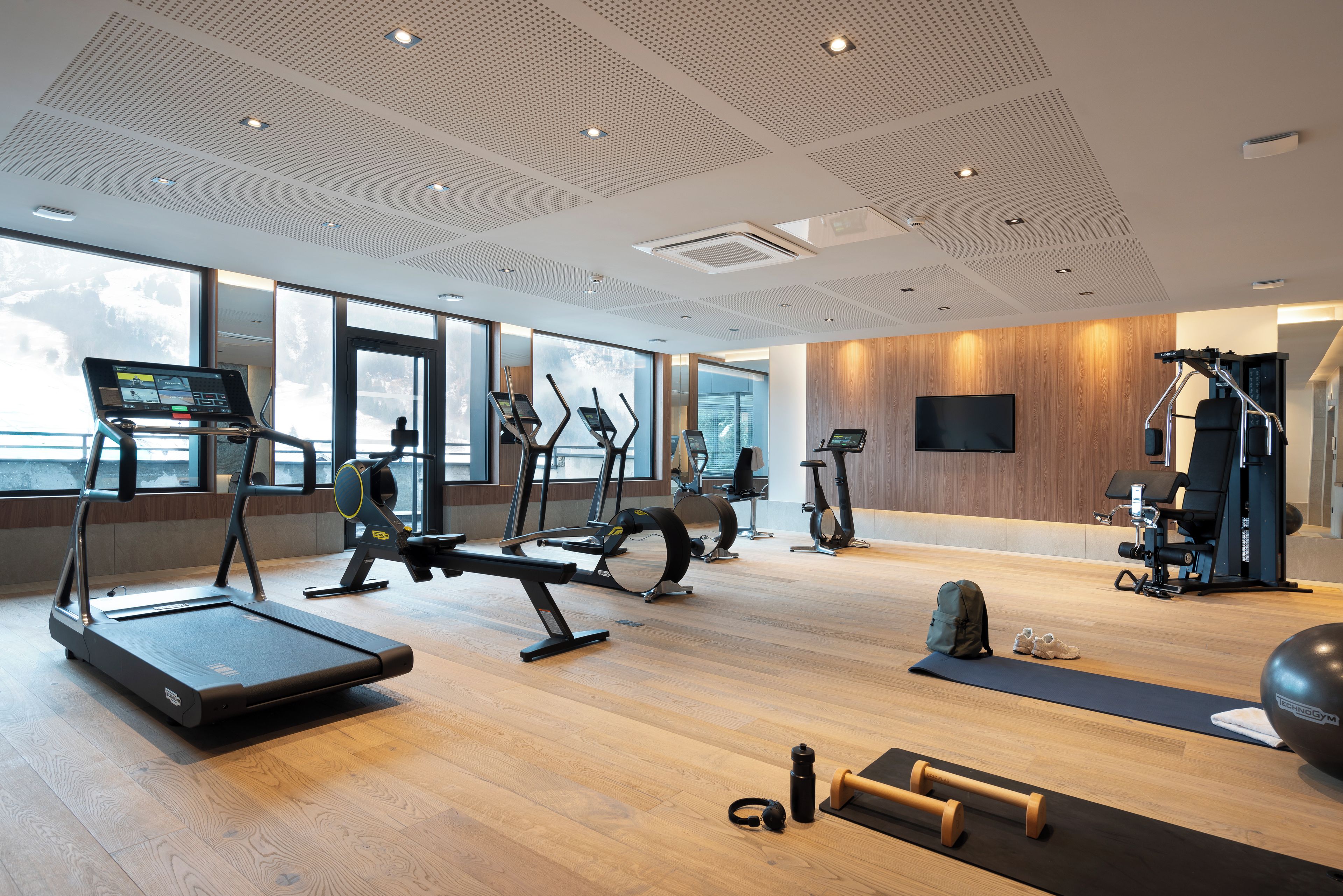 Ein modernes Fitnessstudio mit Laufbändern, Crosstrainern und Kurzhanteln.