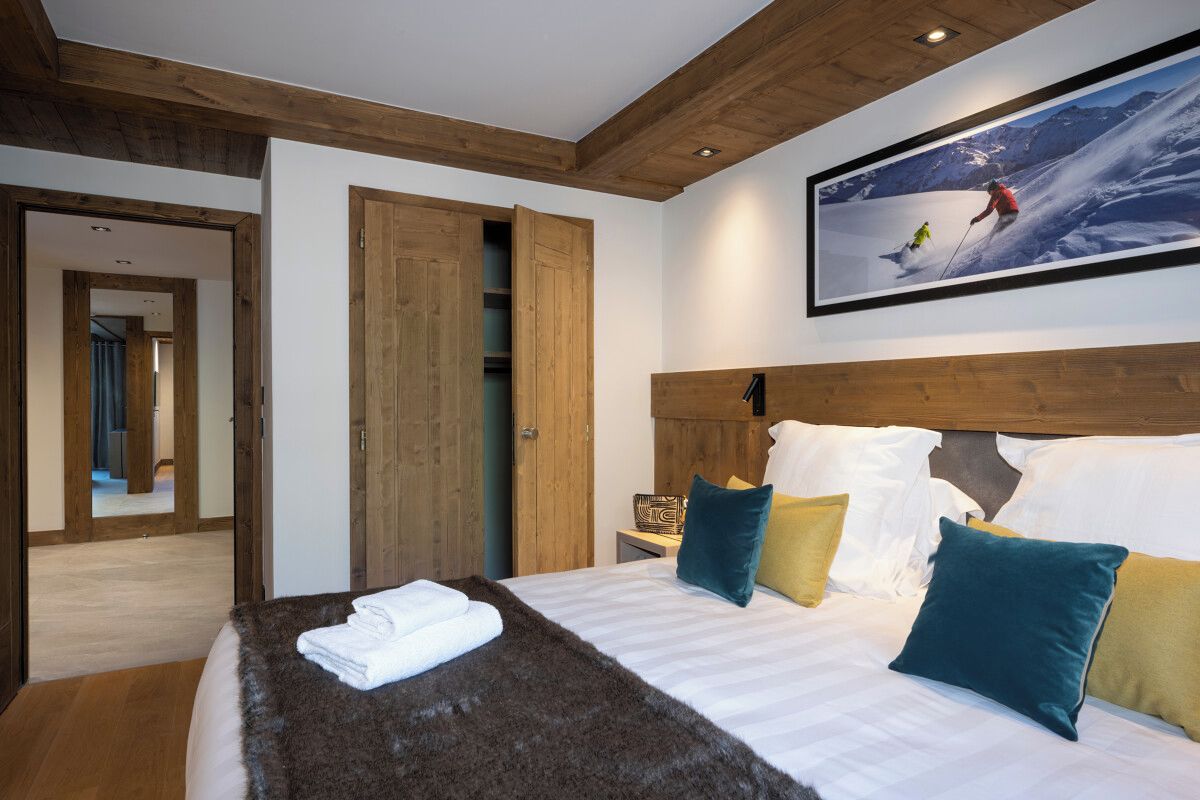 A hotel room with a large bed, wooden headboard, and a ski-themed wall art.