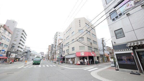 A street view with buildings, a crosswalk, and a green bus. - Ayanishiki Osaka Nishikujo STAY (Osaka)