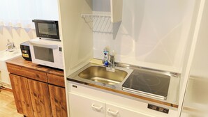 Een kleine keuken met een magnetron, broodrooster en spoelbak.