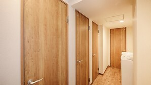 Een hal met houten deuren en een wit apparaat, waarschijnlijk een wasmachine en droger, aan de rechterkant.