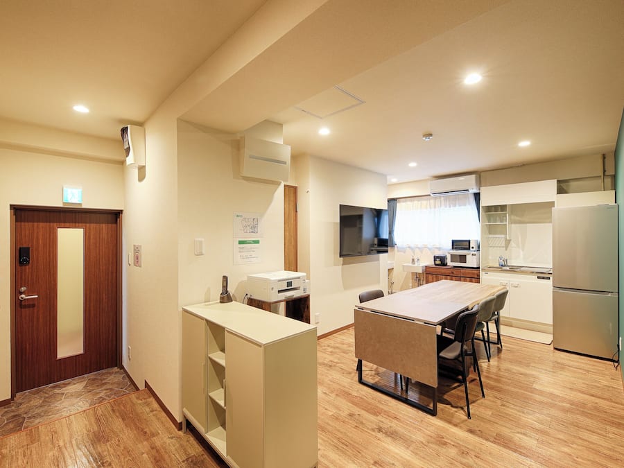 A compact kitchen with a dining area, wooden flooring, and built-in shelves.