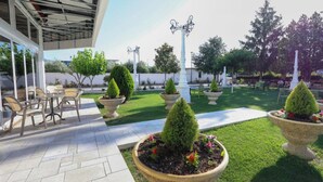 An outdoor patio area with stone flooring, potted plants, and outdoor furniture. - Hotel Familja (Berat)