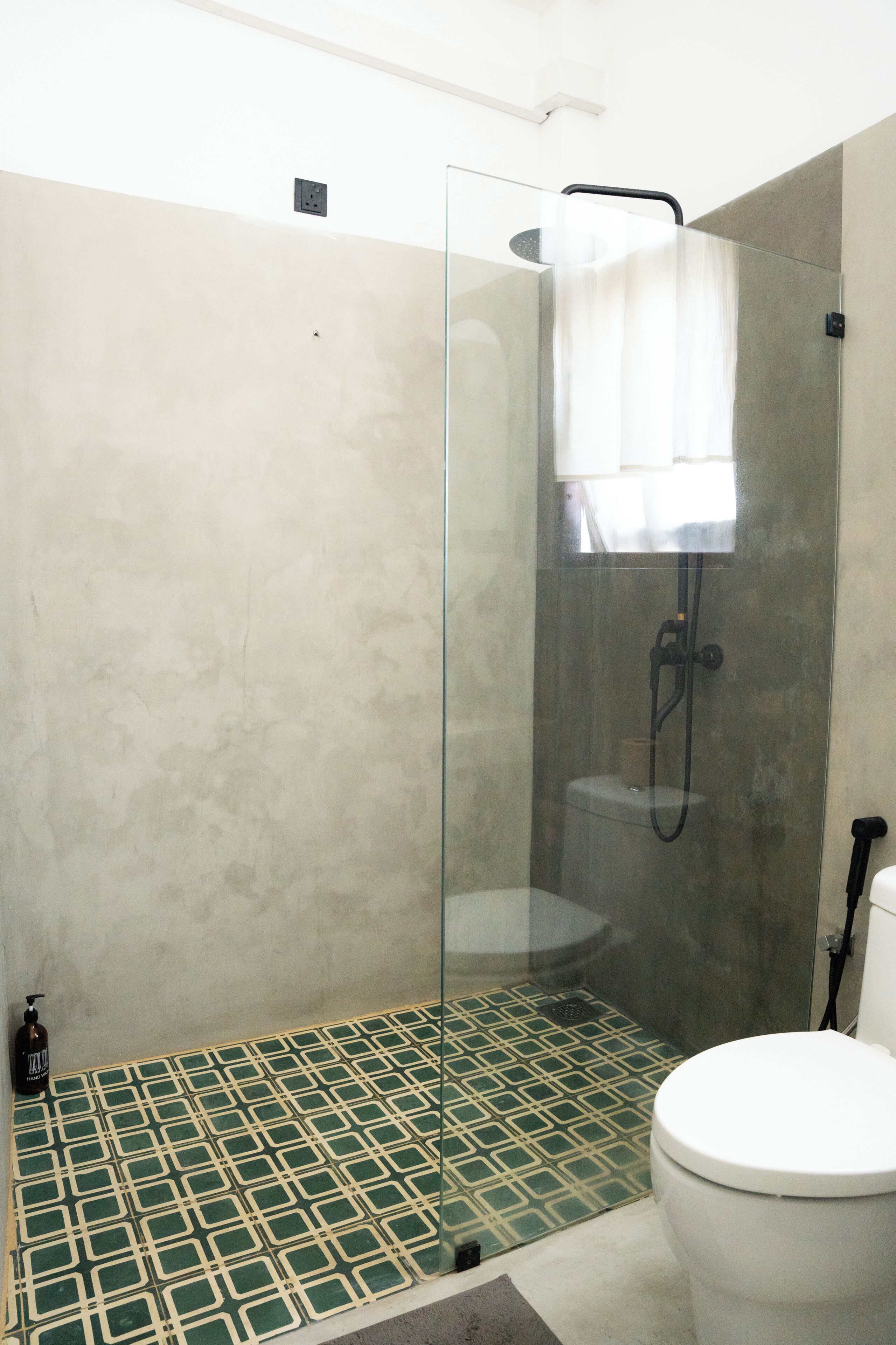 A bathroom with a glass-enclosed shower, a toilet, and a patterned floor.