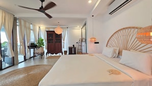 Ein Schlafzimmer mit einem großen Bett, einem Deckenventilator, einer Klimaanlage und Blick durch die Glastür.