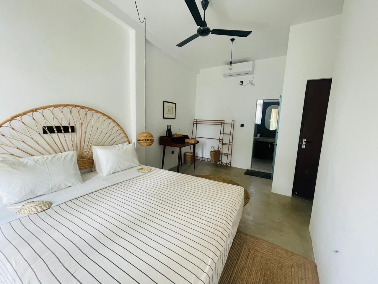 A bedroom with a bed, a ceiling fan, a desk, and a chair.