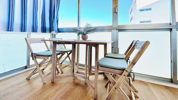 A room with a wooden table and chairs, a potted plant, and a view through large windows. - Lorena. Renovated Apartment with Terrace & Parking (Roses)