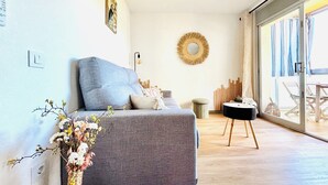 A modern living room with a grey sofa, a round mirror, and a wooden side table. - Lorena. Renovated Apartment with Terrace & Parking (Roses)