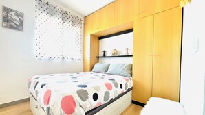 A bedroom with a bed, wooden wardrobe, and a window with curtains. - Lorena. Renovated Apartment with Terrace & Parking (Roses)