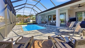 Ein überdachter Außenbereich mit Schwimmbecken, Liegestühlen und einem Patio-Tisch.