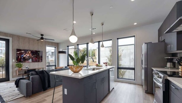 Une cuisine moderne dotée d’un îlot central, de grandes fenêtres et d’un ventilateur de plafond.