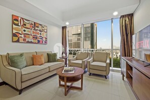 Una sala de estar moderna con un sofá, sillones, una mesa de centro y un cuadro abstracto grande en la pared.