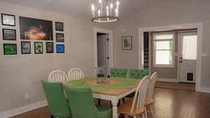 Un comedor con una mesa y sillas de madera, cuadros en la pared y una araña.