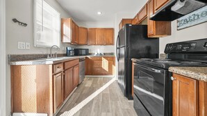 A kitchen with wooden cabinets, a black refrigerator, a stove, and a microwave. - The ATL Escape (Atlanta)