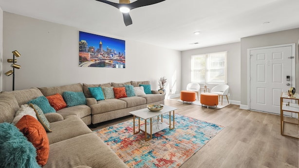 A modern living room with a sectional sofa, a coffee table, and a ceiling fan. - The ATL Escape (Atlanta)