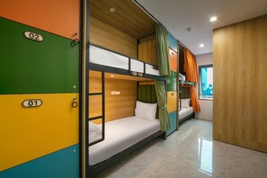 Een slaapkamer met een stapelbed, een houten hoofdeinde, een raam met gordijnen, en een betegelde vloer.