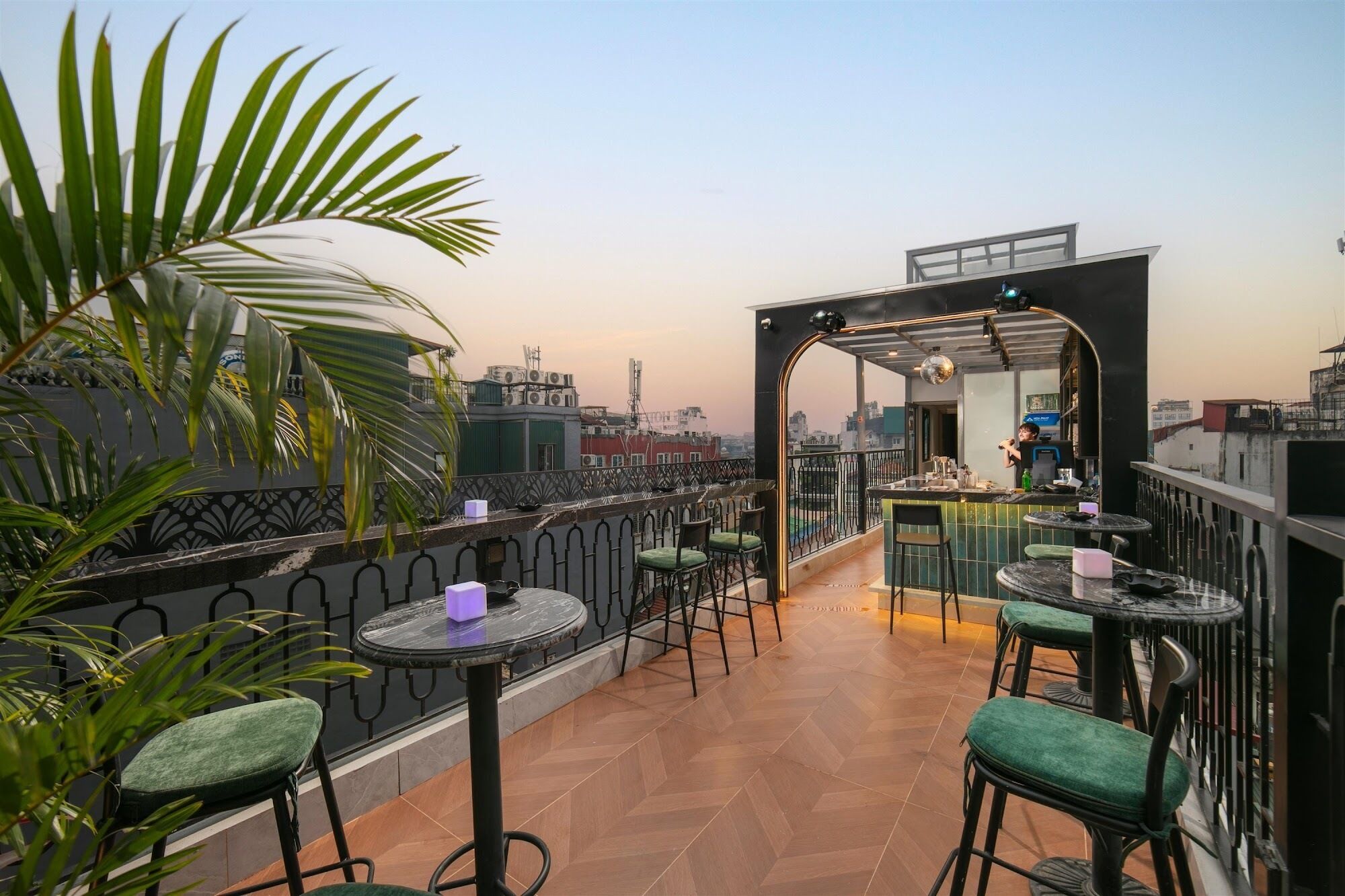A rooftop bar with outdoor seating, a view of the cityscape, and a modern architectural design.