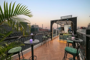 Un bar situé sur le toit, avec une terrasse, une vue sur le paysage urbain et une architecture moderne.