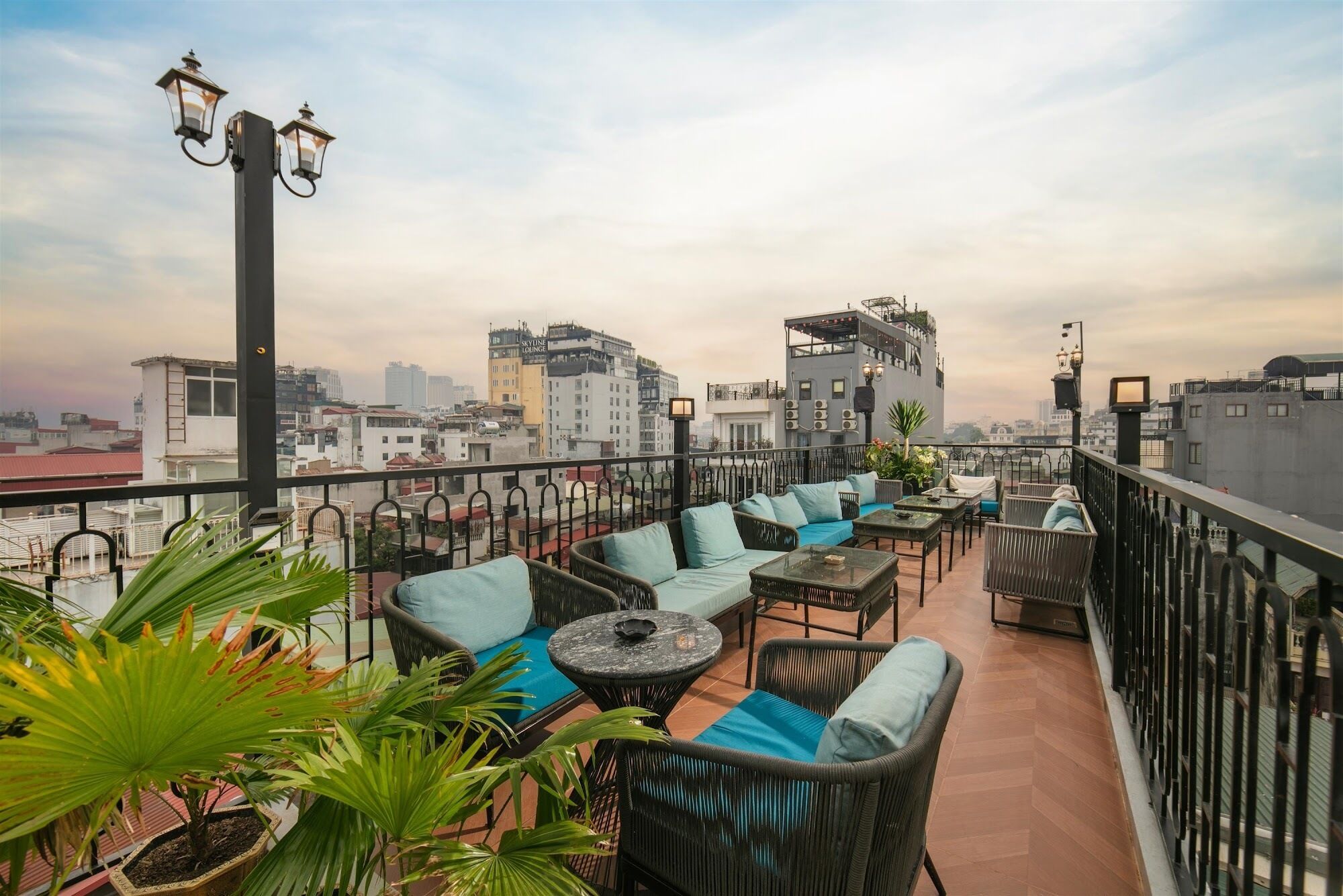 A rooftop terrace with outdoor seating, potted plants, and a city view.