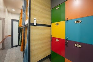 Corredor com armários numerados de 01 a 05, parede de painel de madeira e uma porta com porta-toalhas.