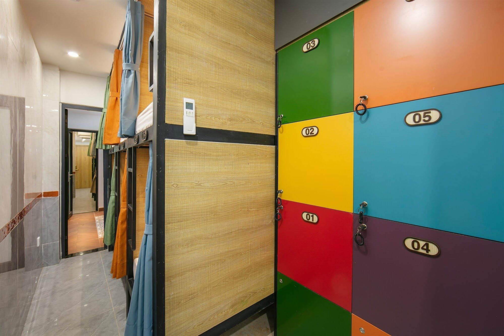 A hallway with lockers numbered 01 to 05, a wooden wall, and a door leading to another room.