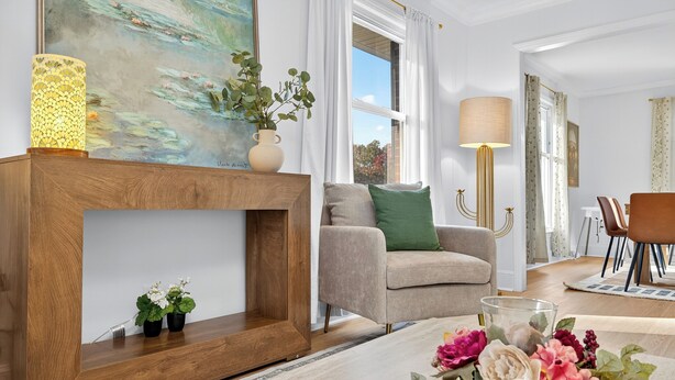 Uma sala de estar moderna com um console de madeira, um sofá bege e uma mesa de centro com arranjos florais.