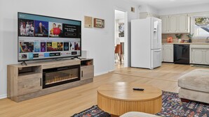 Uma sala de estar moderna com televisão de tela plana, painel de madeira para aparelhos eletrônicos e uma mesa de centro redonda.