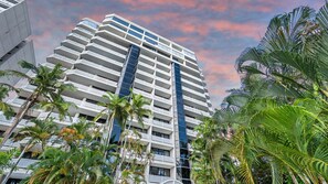 A high-rise hotel with multiple balconies, surrounded by palm trees. - Luxury Oceanview Penthouse at Northshore Tower Cairns (Cairns North)