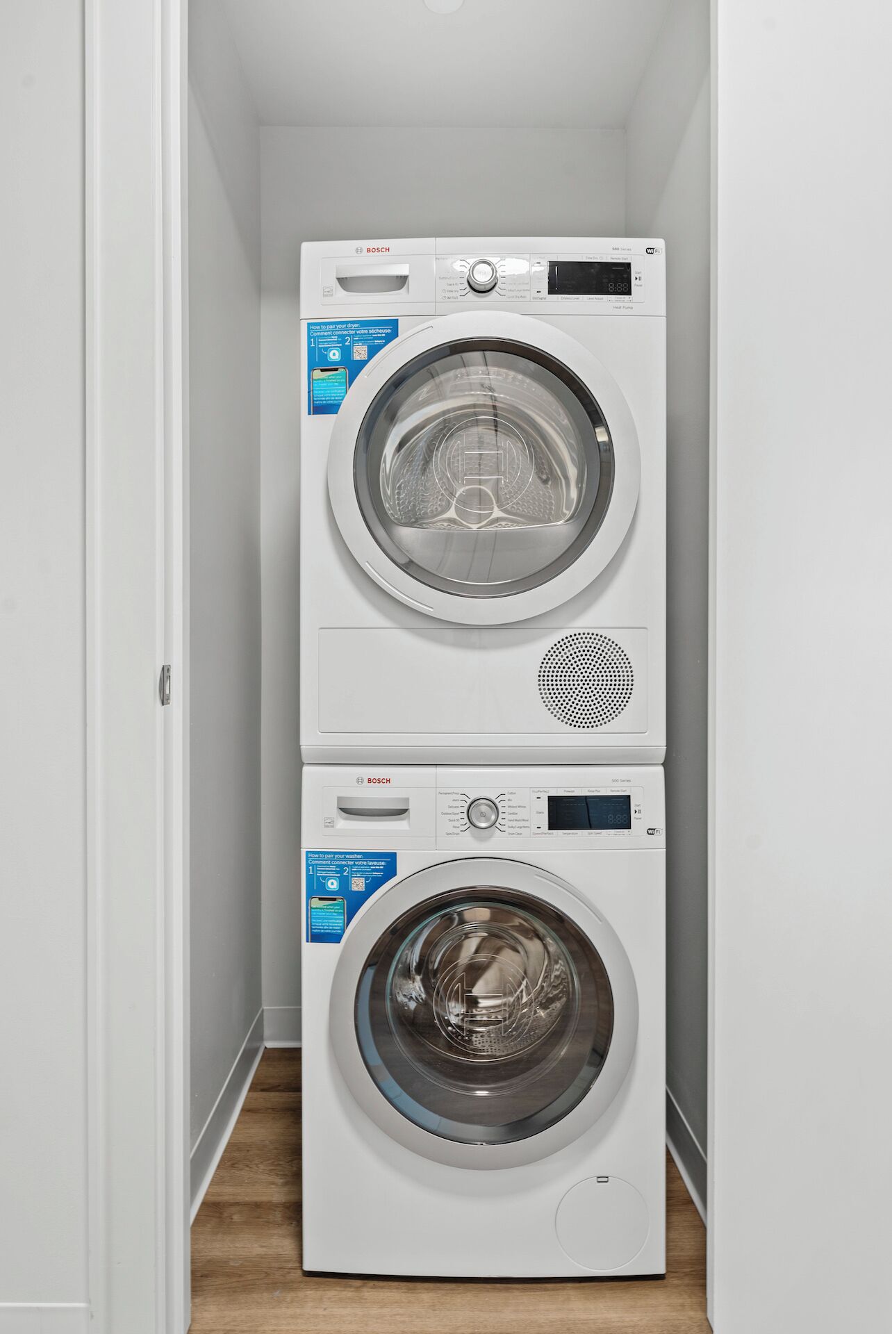 Een gestapelde wasmachine en droger in een smalle gang.
