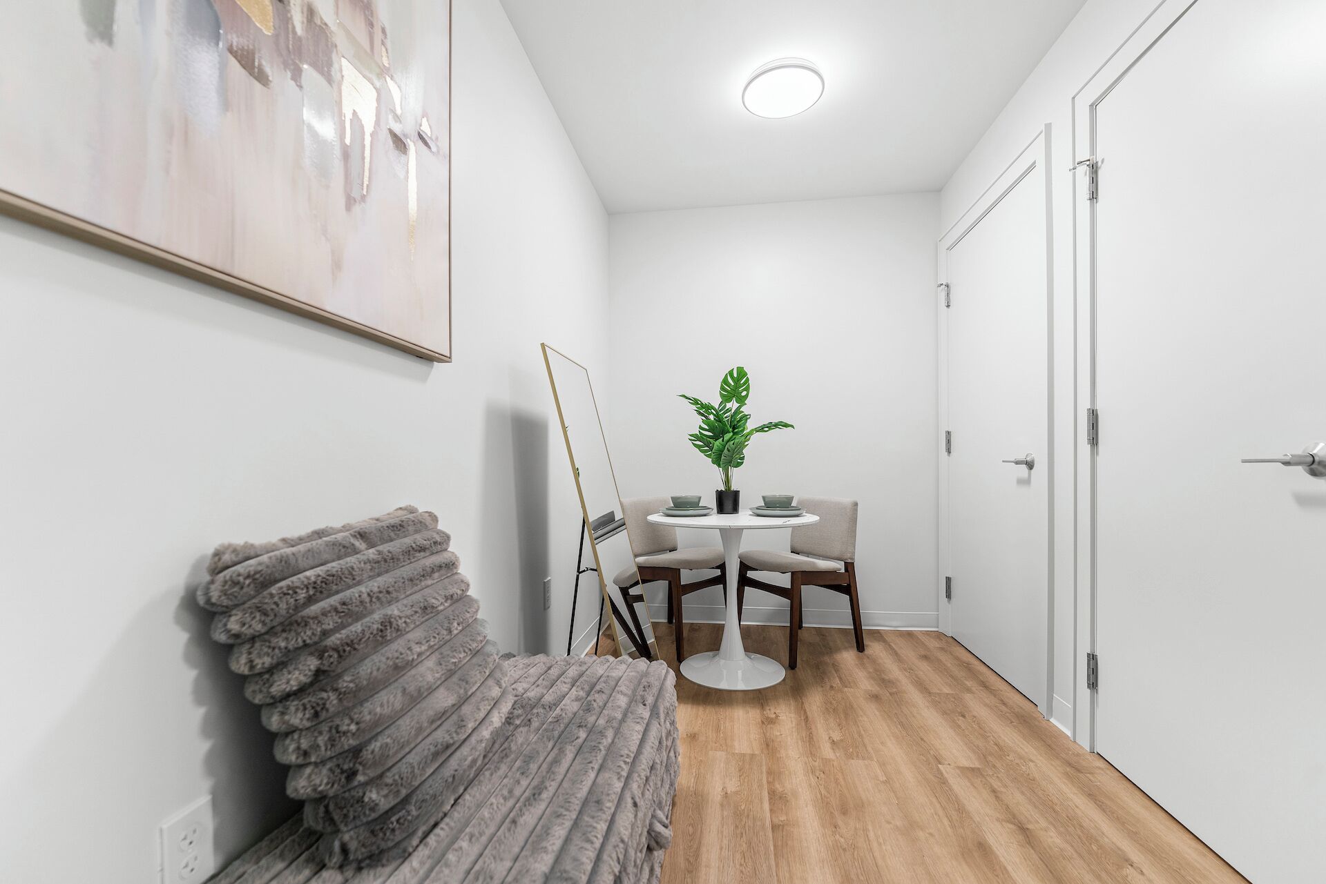 A hallway with a round table, chairs, a potted plant, and a stack of towels.