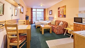 A cozy room with a bed, a sofa, a dining table, and a kitchenette. - Čertovka by Interhome (Harrachov)