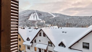 A snow-covered mountain with a ski lift and buildings with snow-covered roofs. - Čertovka by Interhome (Harrachov)