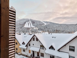 A snow-covered mountain with a ski lift and buildings with snow-covered roofs. - Čertovka by Interhome (Harrachov)