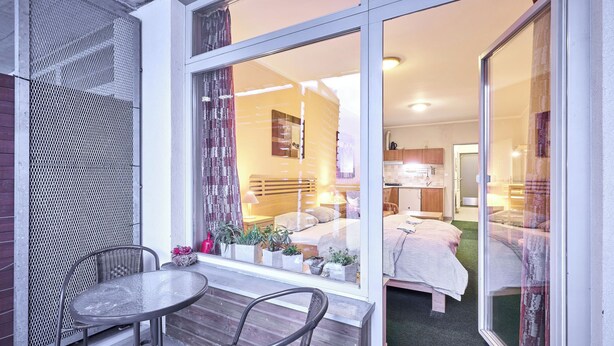 A modern hotel room with a large sliding glass door leading to a balcony with a table and chairs. - Čertovka by Interhome (Harrachov)