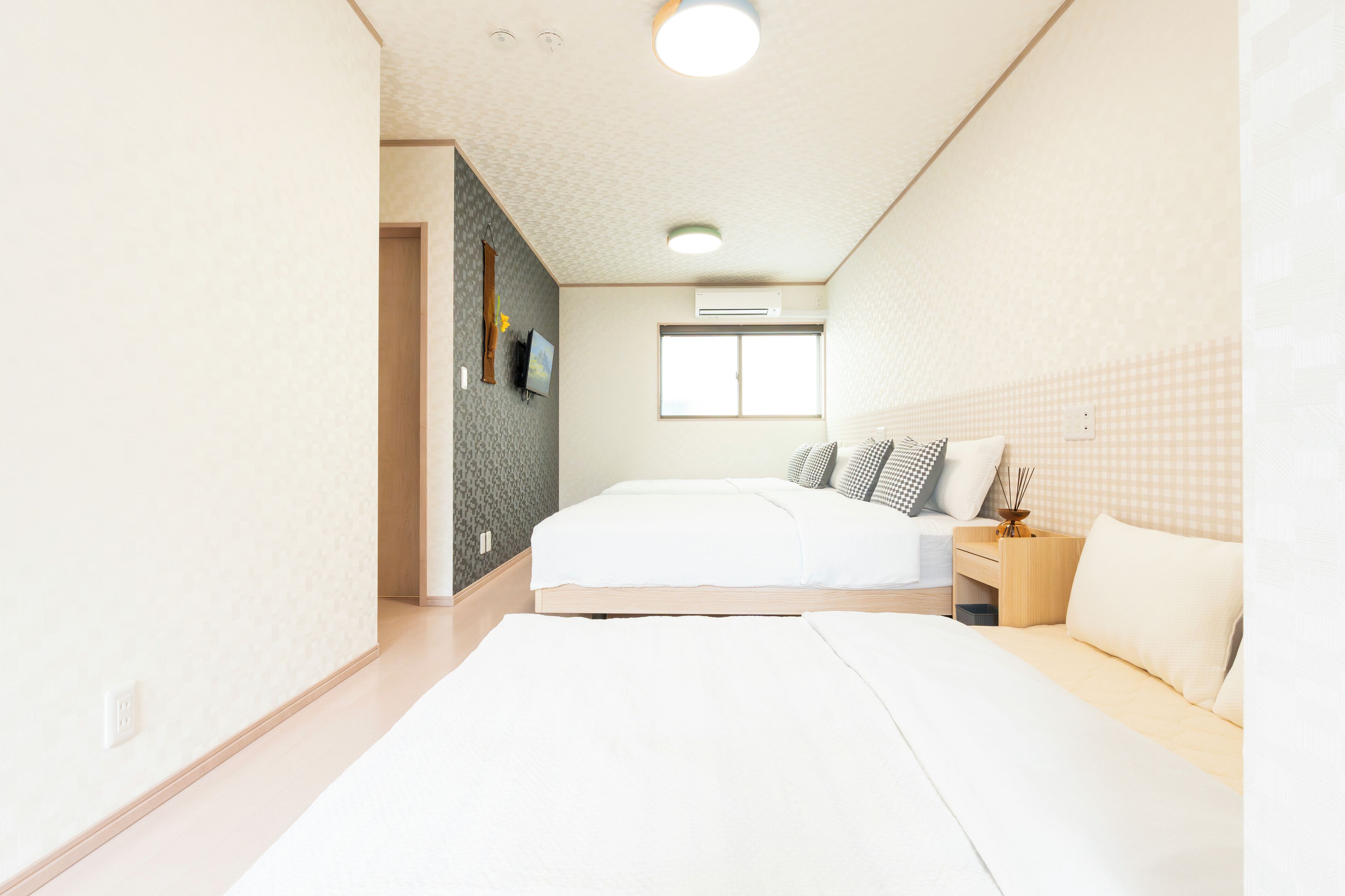 A modern bedroom with a large bed, bedside tables, a window, and an air conditioning unit.