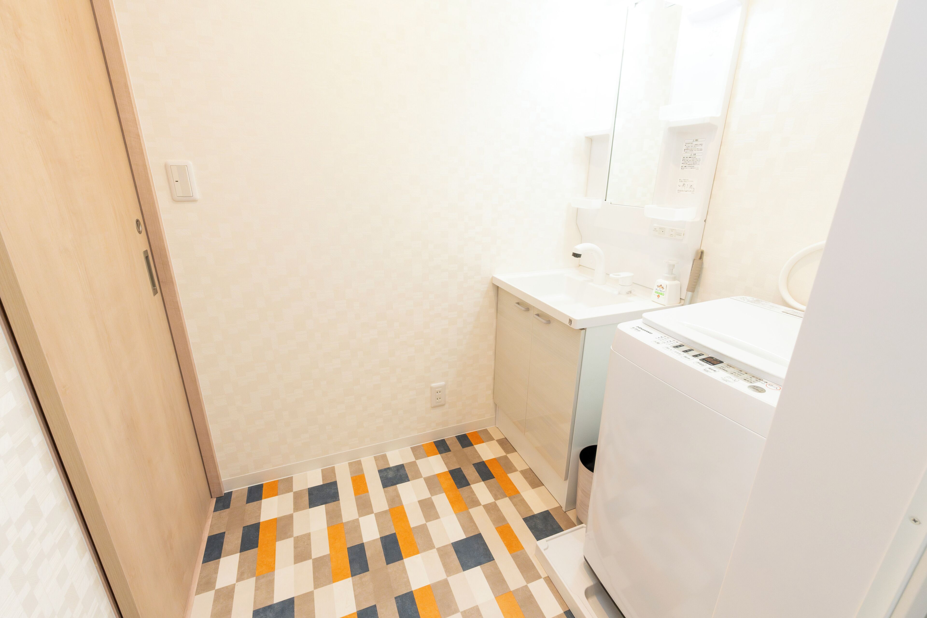 Un bagno piccolo con pavimento piastrellato, un lavandino bianco e una lavatrice.