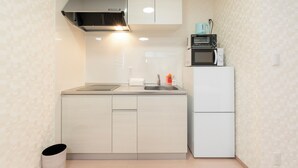 A compact kitchen with a microwave, toaster, and a small refrigerator. - Air Station Front Stay (Izumisano)